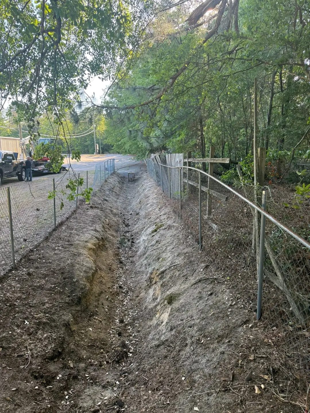 TCB Farms & Clearing drainage project — ditch dug alongside a fence line